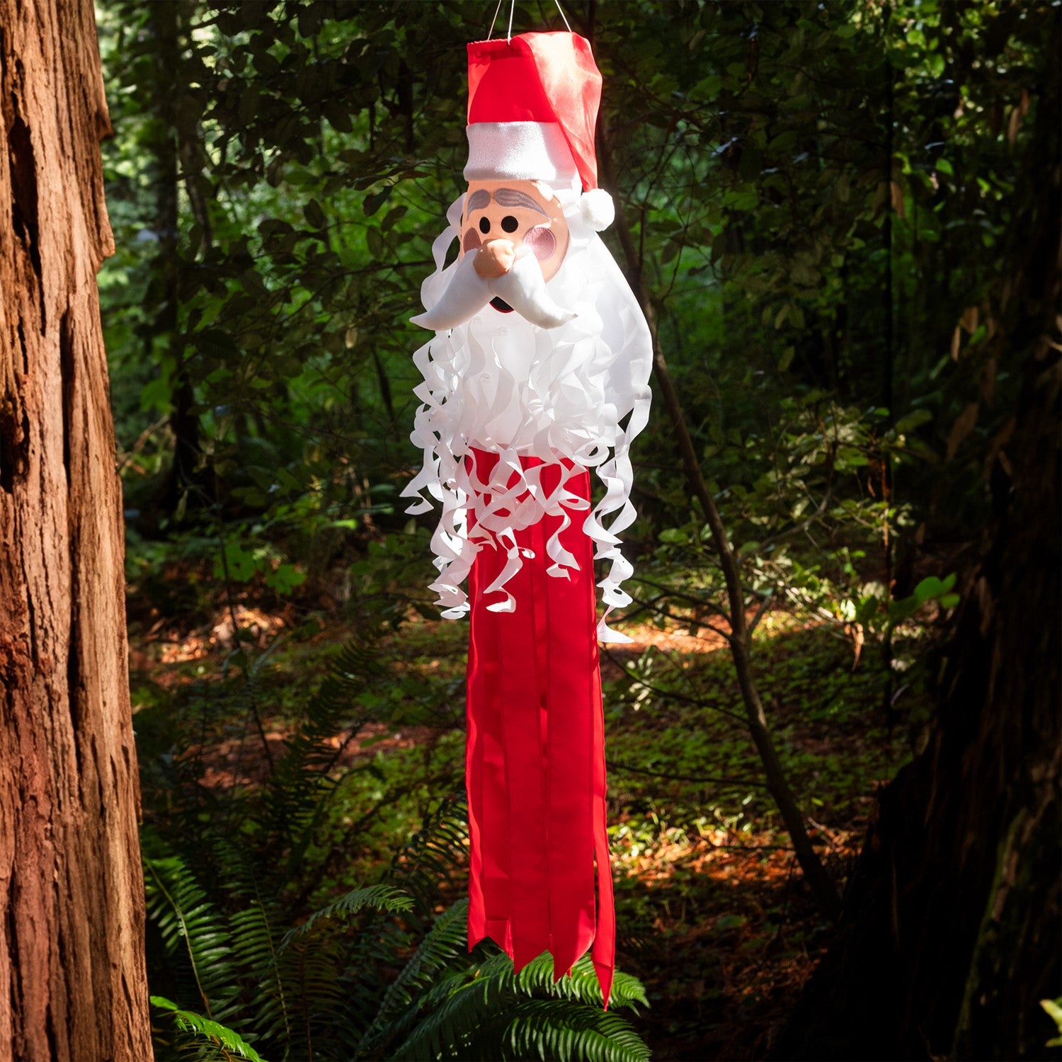 Santa 3D Windsock featuring a cheerful Santa face with curly beard and textured hat, hanging decoratively outdoors in a festive setting.
