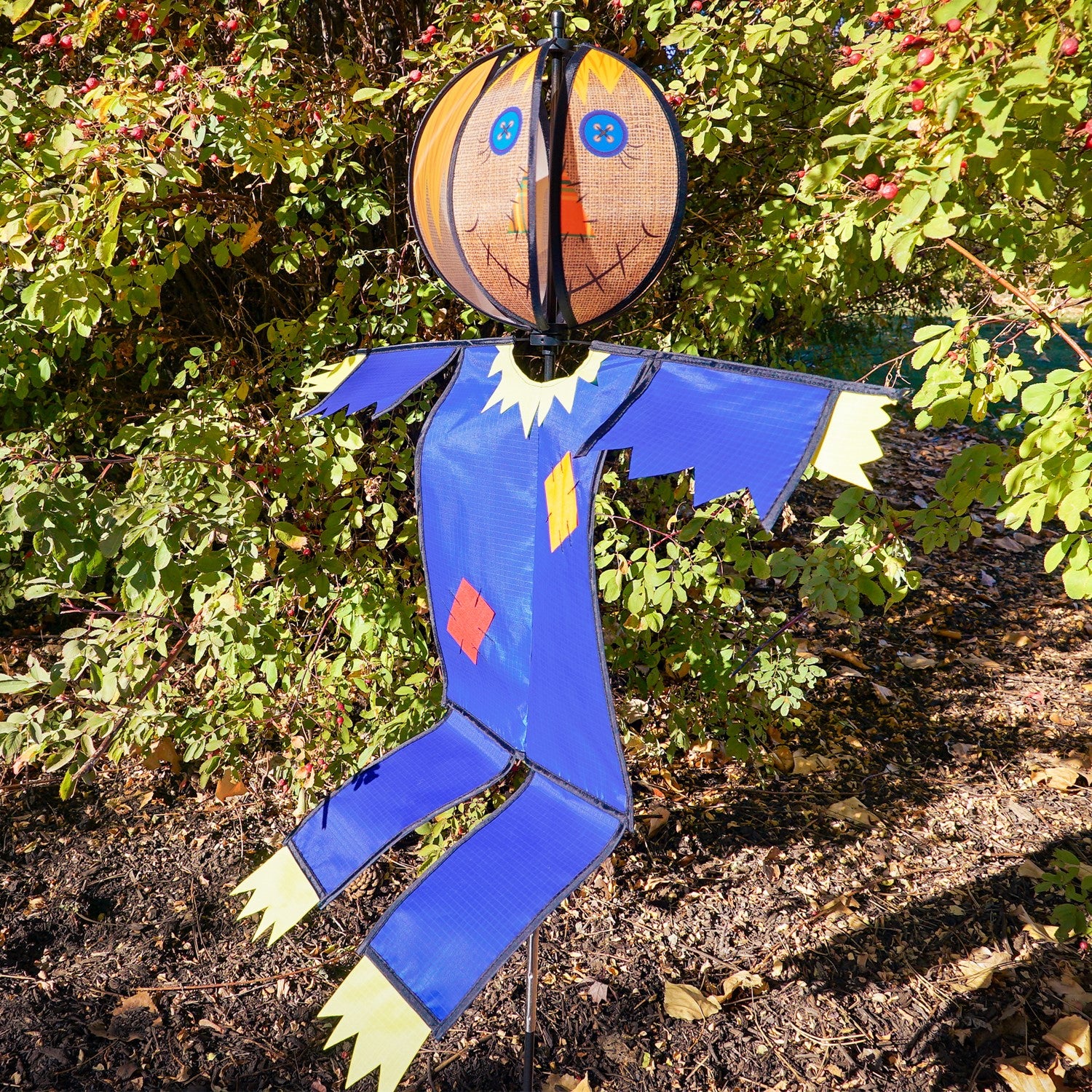 Colorful Scarecrow Ground Ball Spinner spinning in a garden setting, showcasing a friendly face with vibrant colors and durable design.