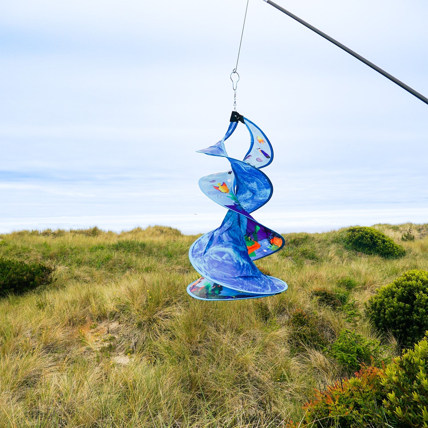 Sea Swimmers Spin Duet hanging garden decor featuring vibrant sea turtles spinning against a backdrop of ocean waves in an outdoor setting.