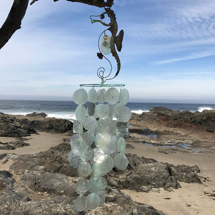 Seahorse Capiz Breeze Wind Chime featuring vibrant Capiz shells shaped like seahorses, hanging elegantly in a garden setting.