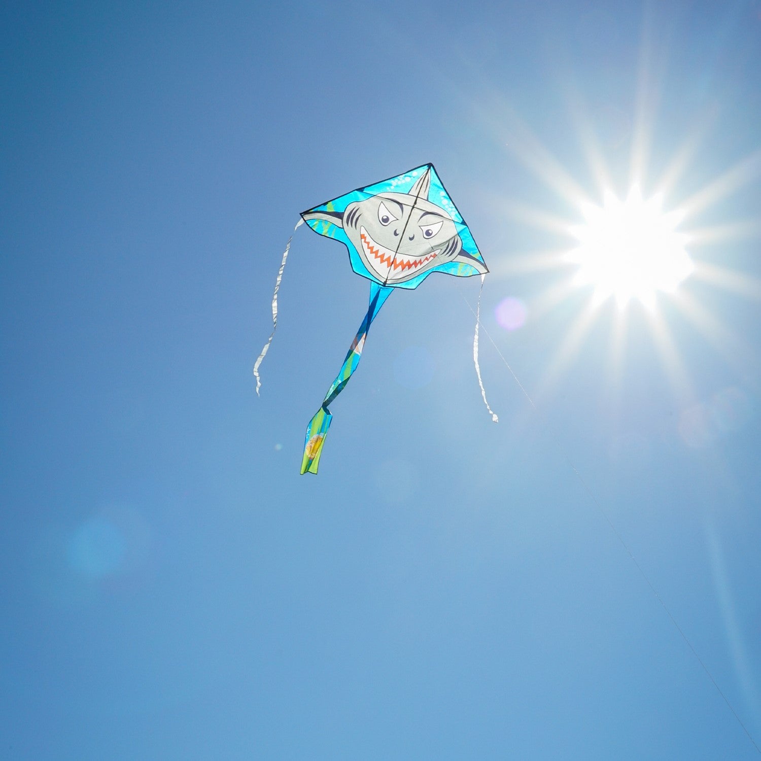 Shark Attack 45' Fly-Hi Kite featuring a Great White shark design soaring against a clear blue sky during a family outing in a park.