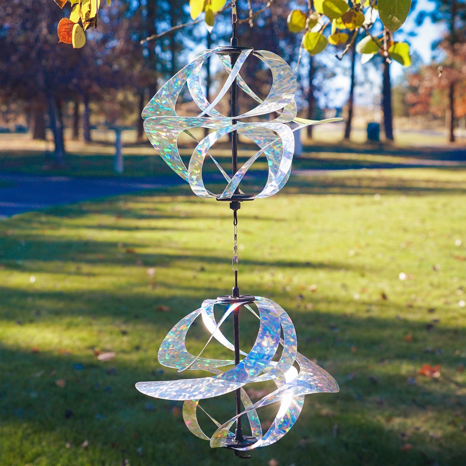 Silver Sparkle Vortex Double Spinner featuring interconnected Mylar spirals, elegantly spinning in an outdoor garden setting.