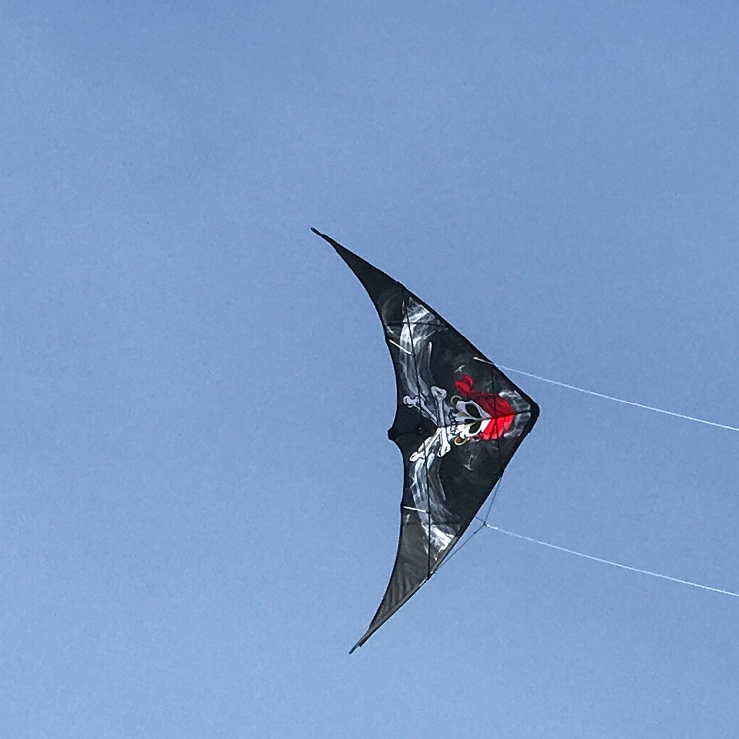 Smokin' Pirate 48" Sport Kite soaring in the sky with a Jolly Roger design, showcasing its vibrant colors against a sunny backdrop.