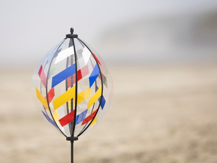 Spinning Lantern featuring six colorful weather-resistant panels spinning in the garden, standing tall at 41.5 inches with a pointed pole for easy ground insertion.