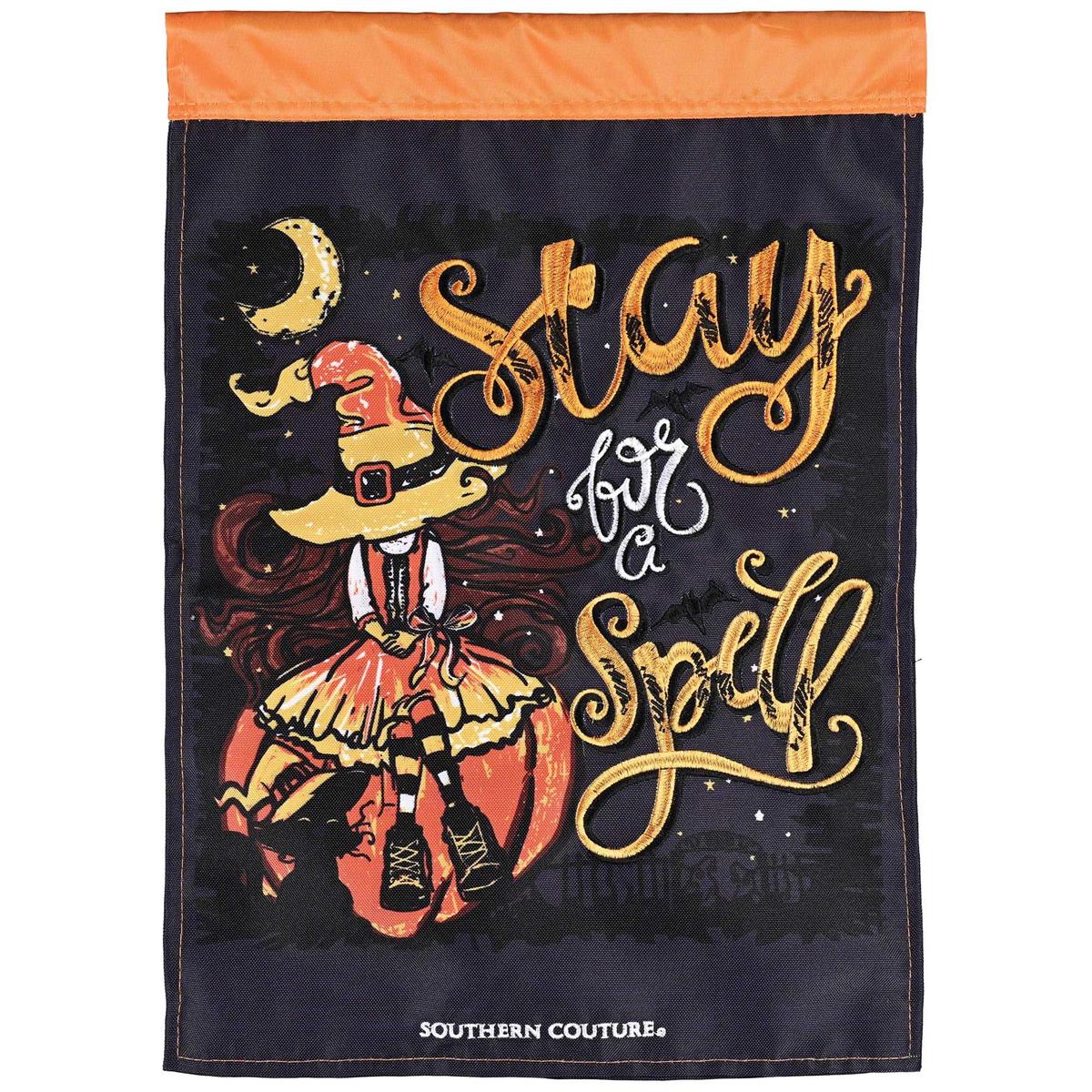 Stay For A Spell double-applique garden flag featuring fall motifs displayed on a decorative stand in an outdoor garden setting.