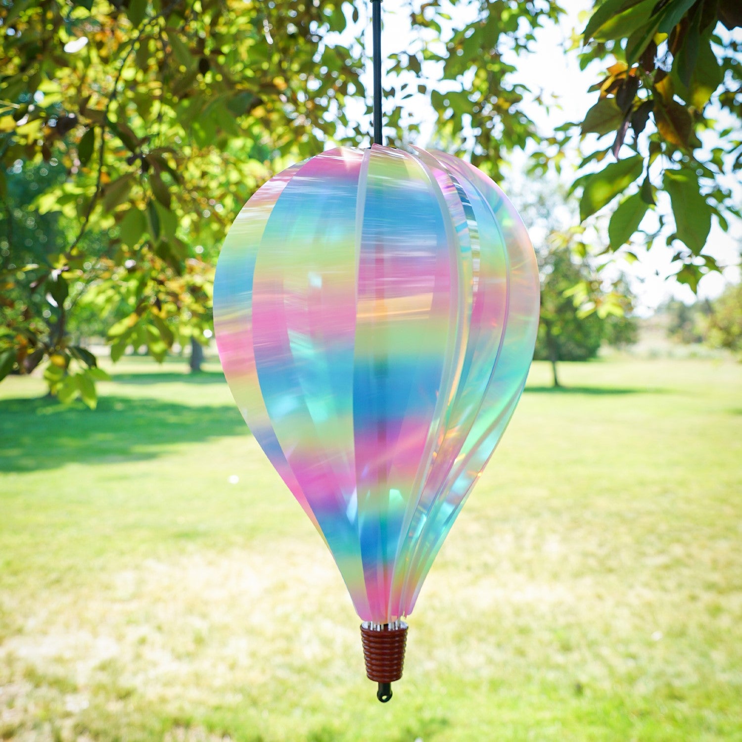 Striped Iridescent 10-Panel Hot Air Balloon spinner, showcasing vibrant colors and smooth spinning action, hanging outdoors amongst greenery.