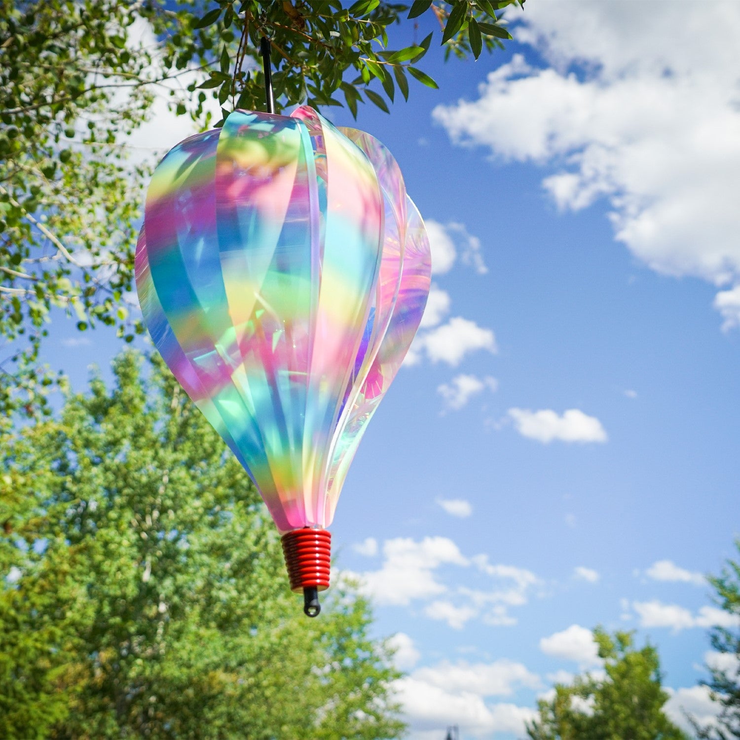 Striped Iridescent 10-Panel Hot Air Balloon spinner, showcasing vibrant colors and smooth spinning action, hanging outdoors amongst greenery.
