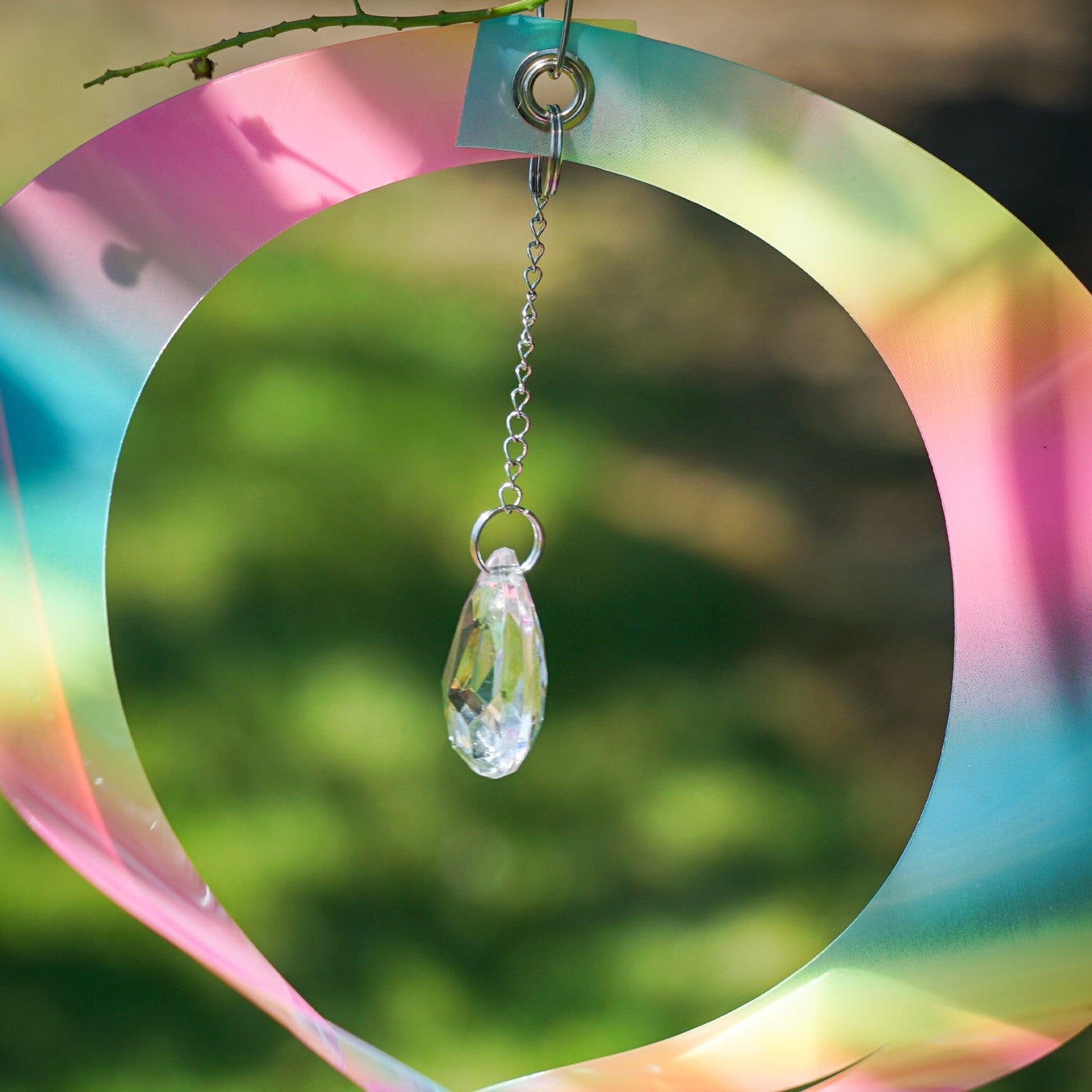 Striped Iridescent Mylar Spin Quartet displayed outside with colorful reflections and a crystal hanging from a chain, spinning elegantly in the breeze.