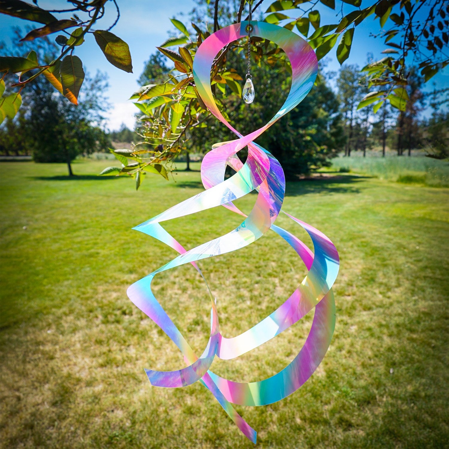 Striped Iridescent Mylar Spin Quartet displayed outside with colorful reflections and a crystal hanging from a chain, spinning elegantly in the breeze.