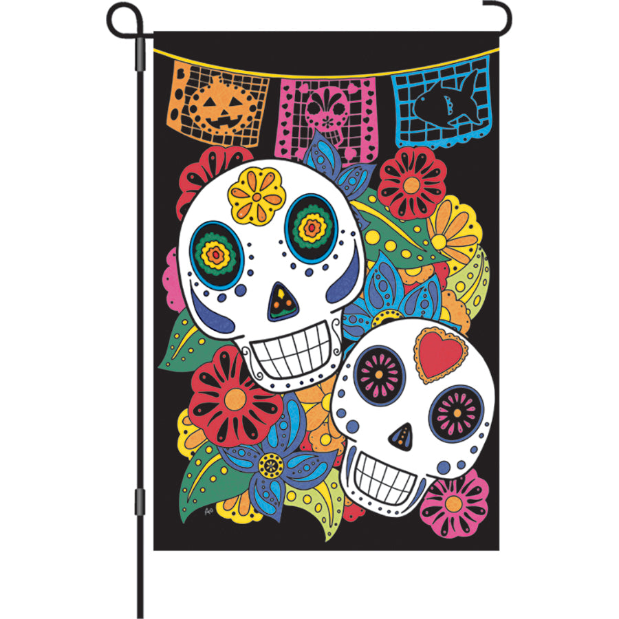 12 in. Sugar Skulls garden flag featuring vibrant sugar skull designs, illuminated for extra brightness, displayed in an outdoor garden setting.