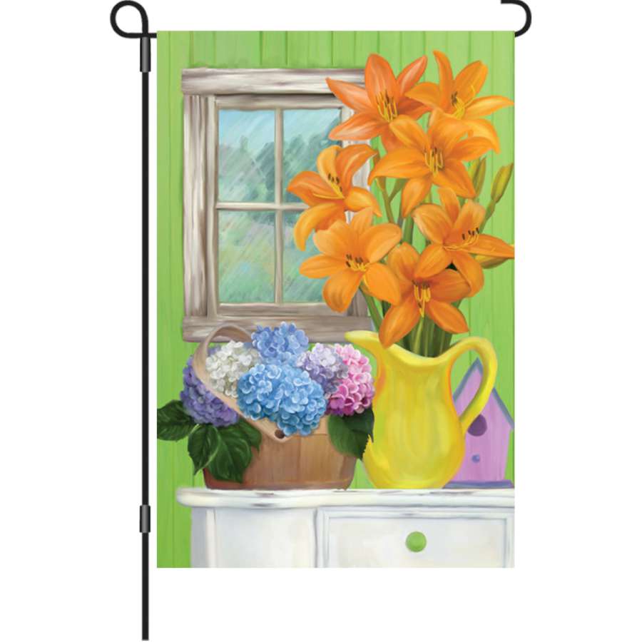 12 Inch Summer Flowers garden flag featuring bright floral designs, displayed outdoors with illumination at dusk, adding color to the garden.