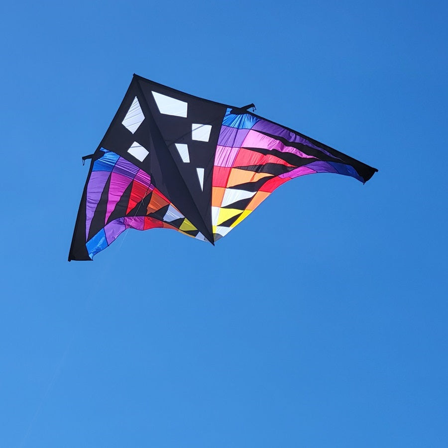 Sweet 16 Delta Kite - Sunset Check, featuring vibrant colors and a large design, soaring high against an open blue sky during outdoor flight.
