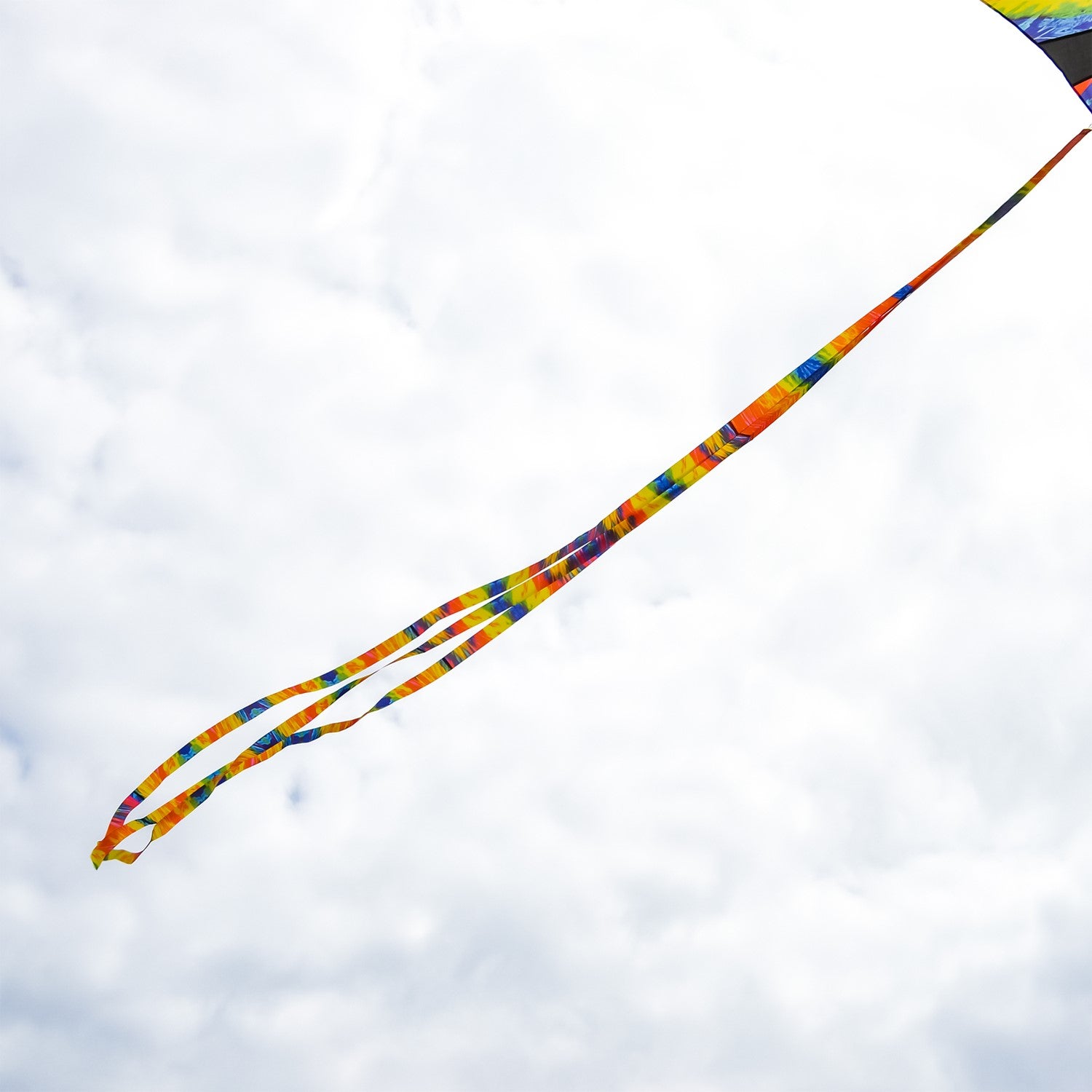 Set of three colorful 15' Tie Dye tails displayed in the wind, attached to a kite during an outdoor kite flying event.
