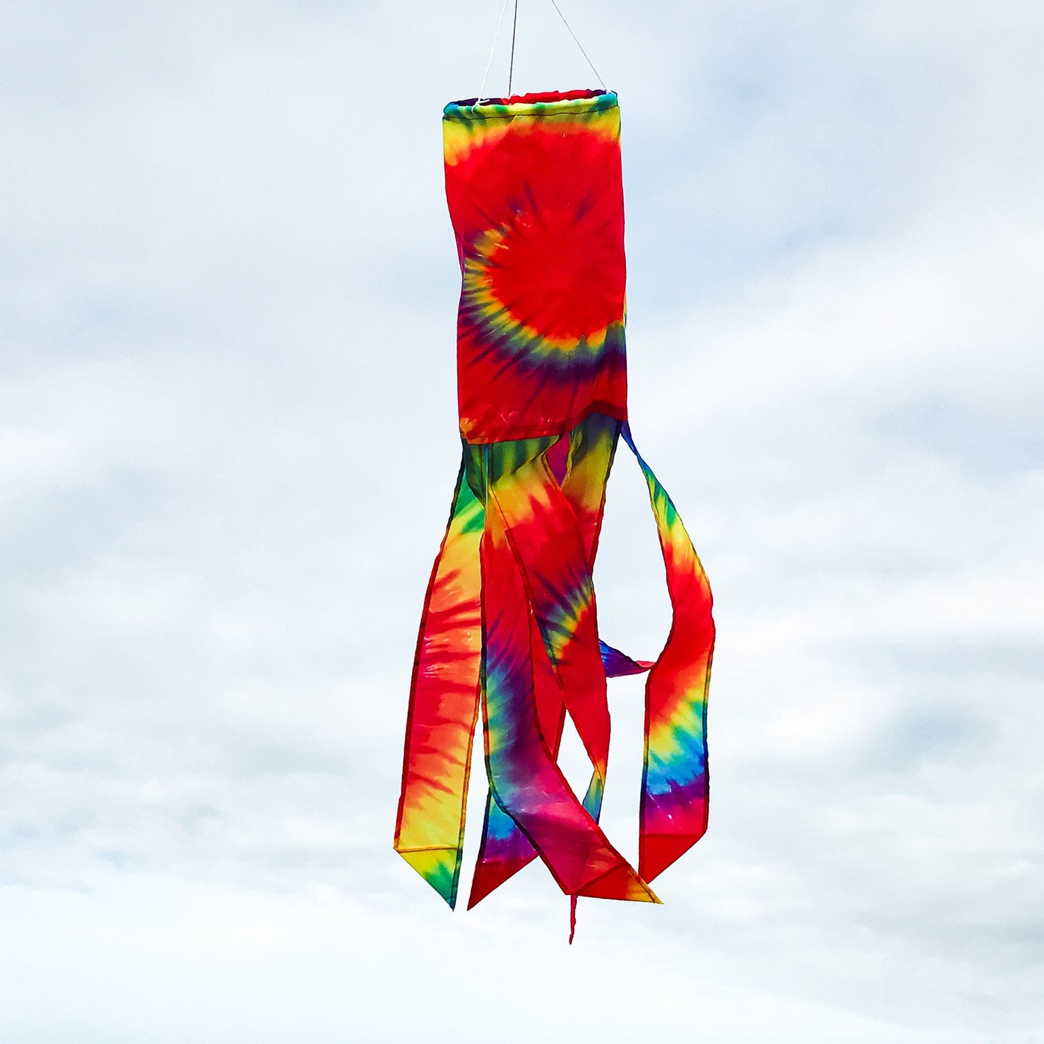 Tie Dye 30\" Windsock featuring a colorful spiral design with six flowing tails, elegantly hanging outdoors in a vibrant setting.