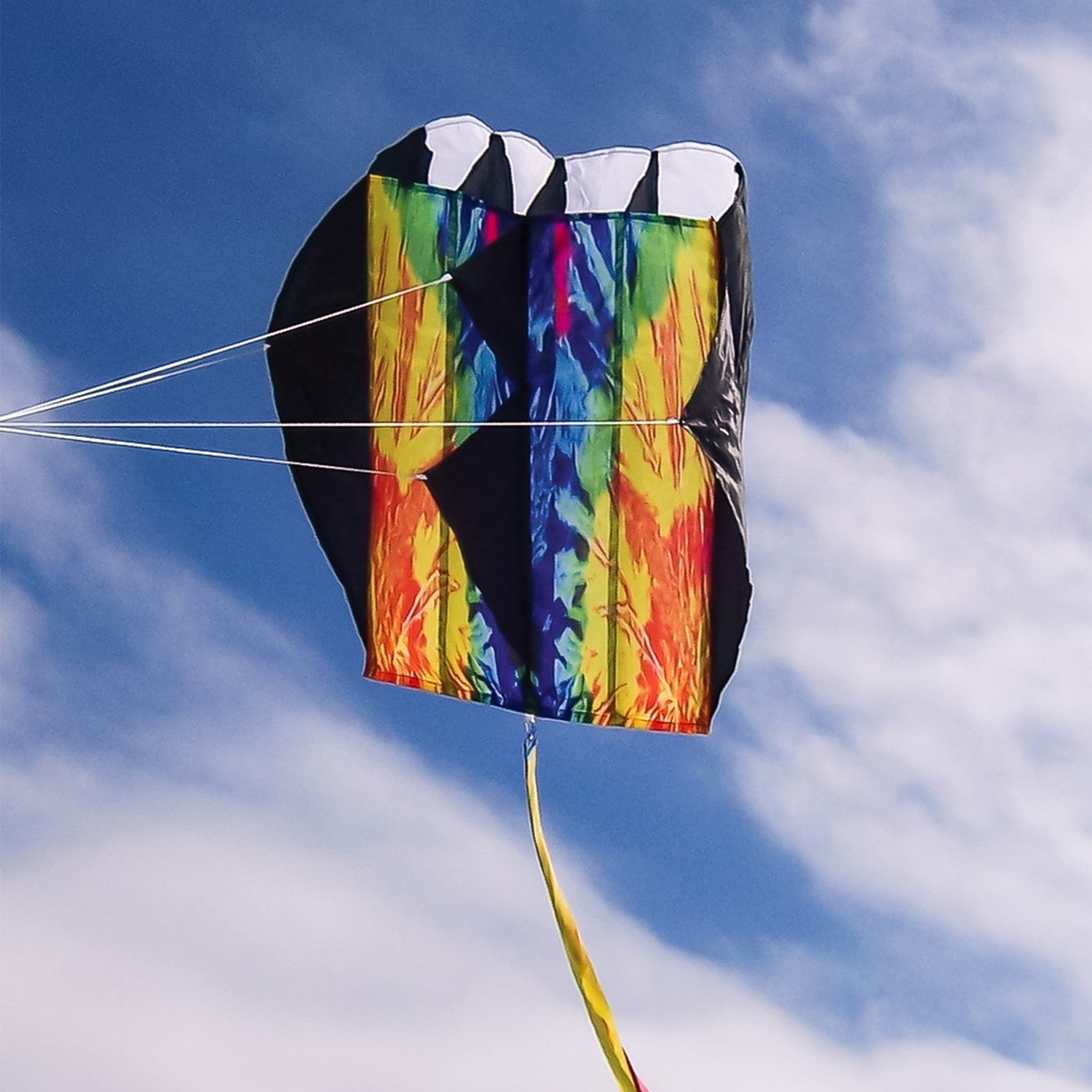Tie Dye Pouch Parafoil Kite soaring in the blue sky, featuring a colorful design and three coordinating kite tails.