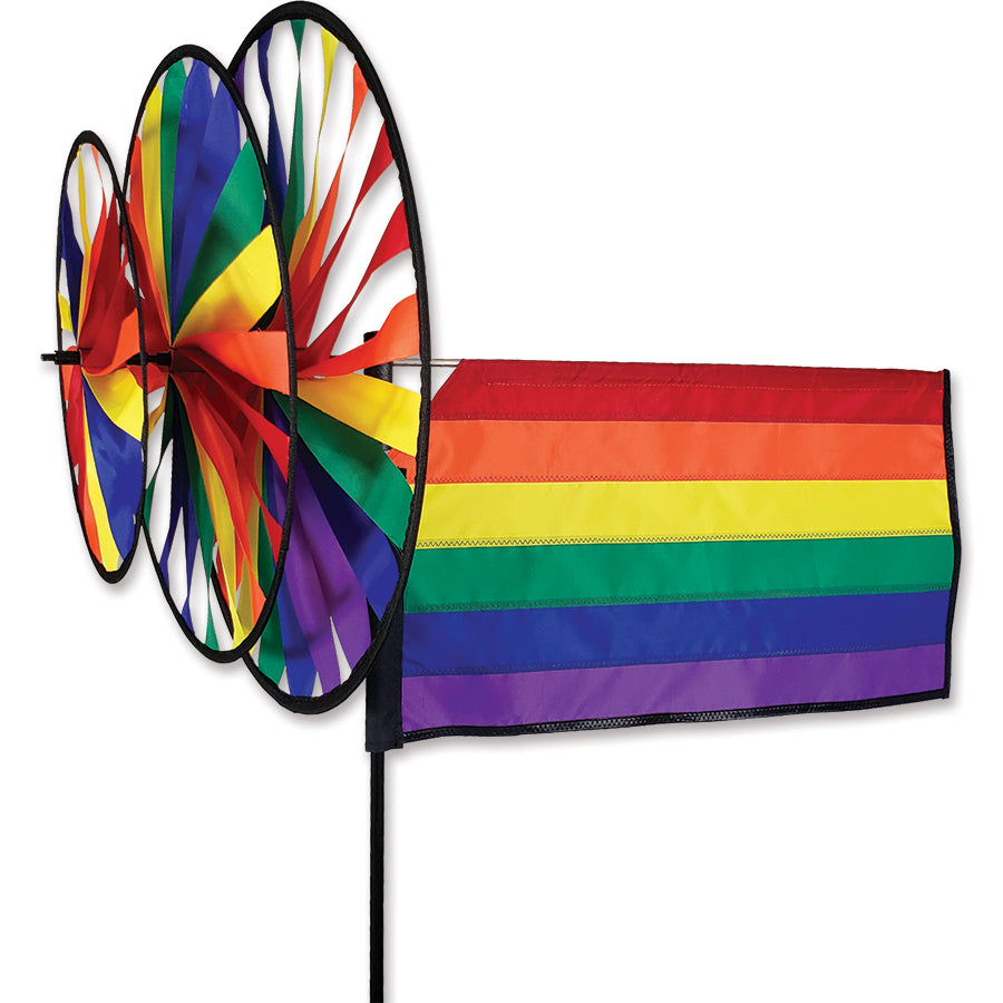 Triple Spinner - Rainbow Flag with vibrant colors spinning gracefully in a garden setting, showcasing its durable and fade-resistant SunTex fabric.