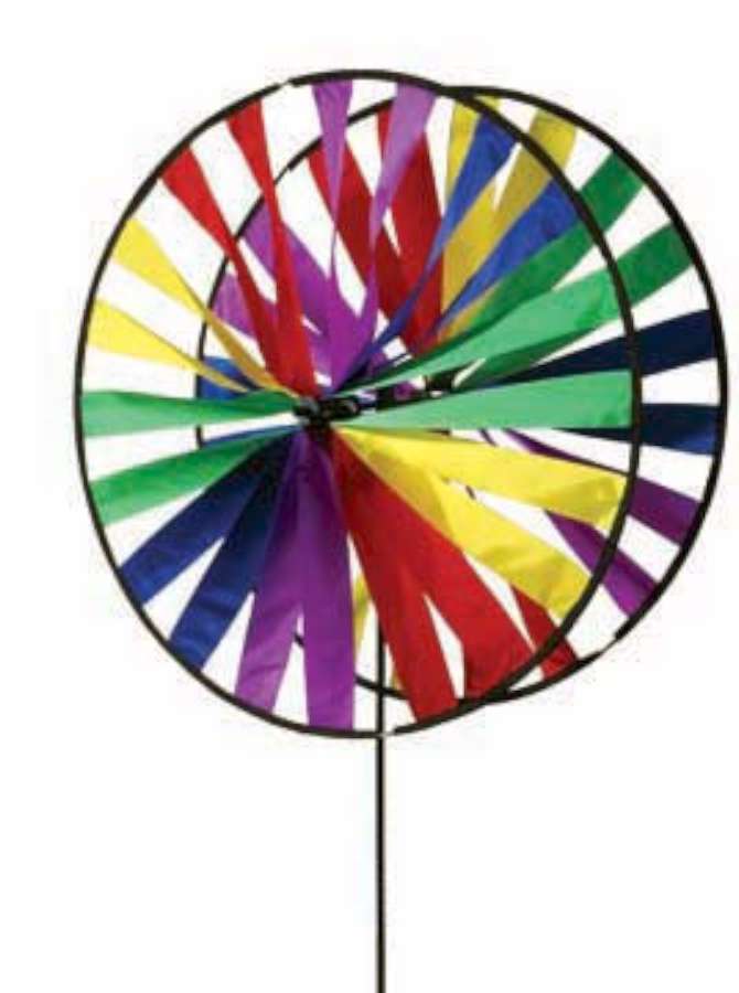 Twin Wheel Spinner - 48 In. with colorful, counter-spinning wheels creating a rainbow effect in a garden setting on a sunny day.