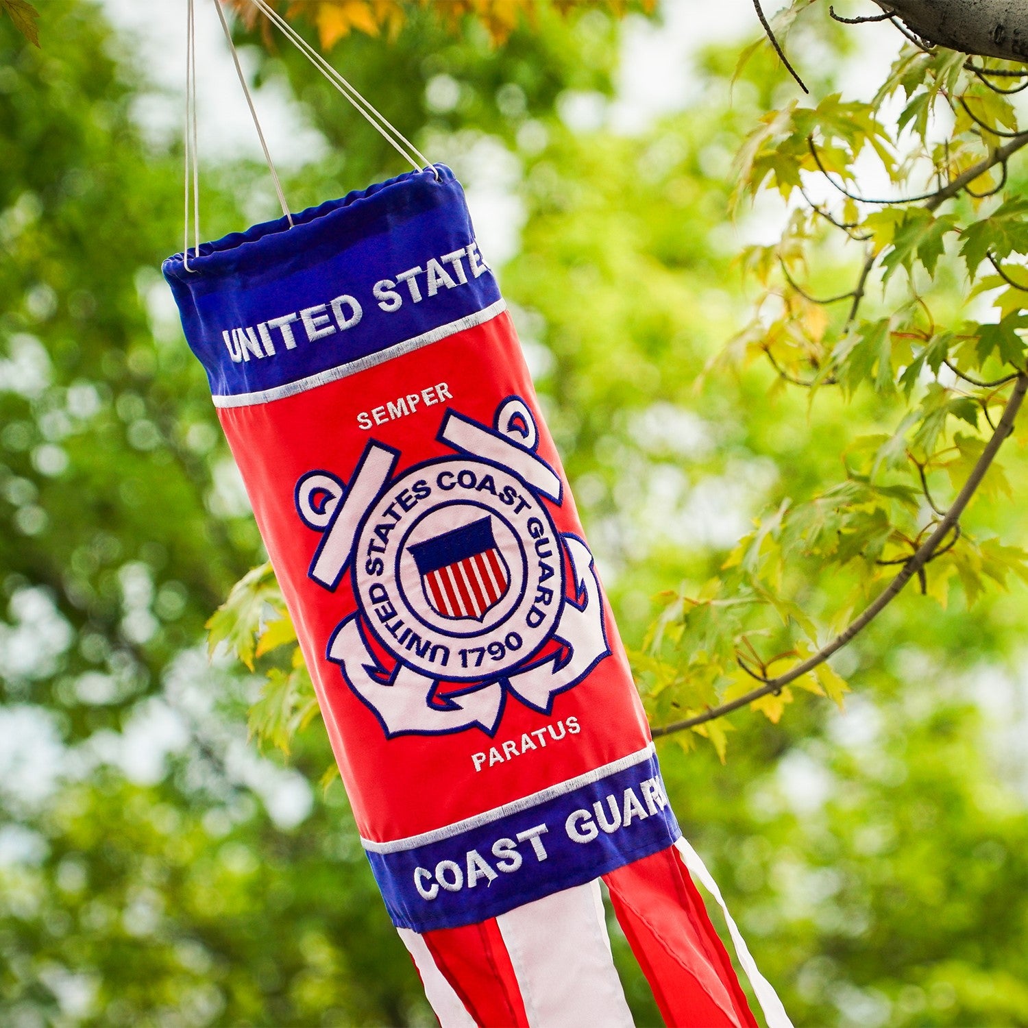 U.S. Coast Guard 40 inch windsock with detailed appliqued graphics and embroidered accents, fluttering outdoors in a garden setting.