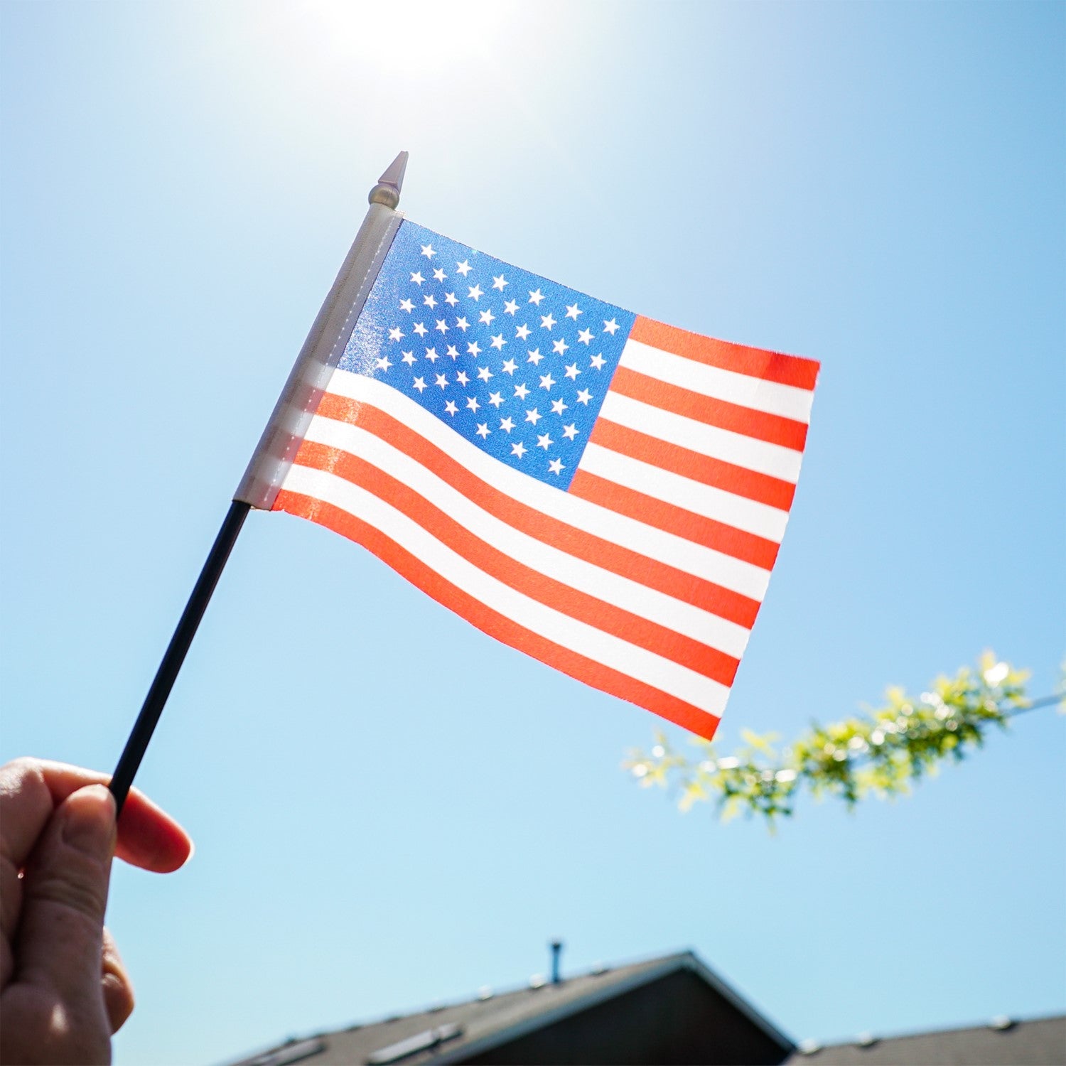 U.S. Flag 4x6 Stick Flag with vibrant stars and stripes on a black stick, ideal for holiday celebrations and outdoor decor displayed at a gathering.
