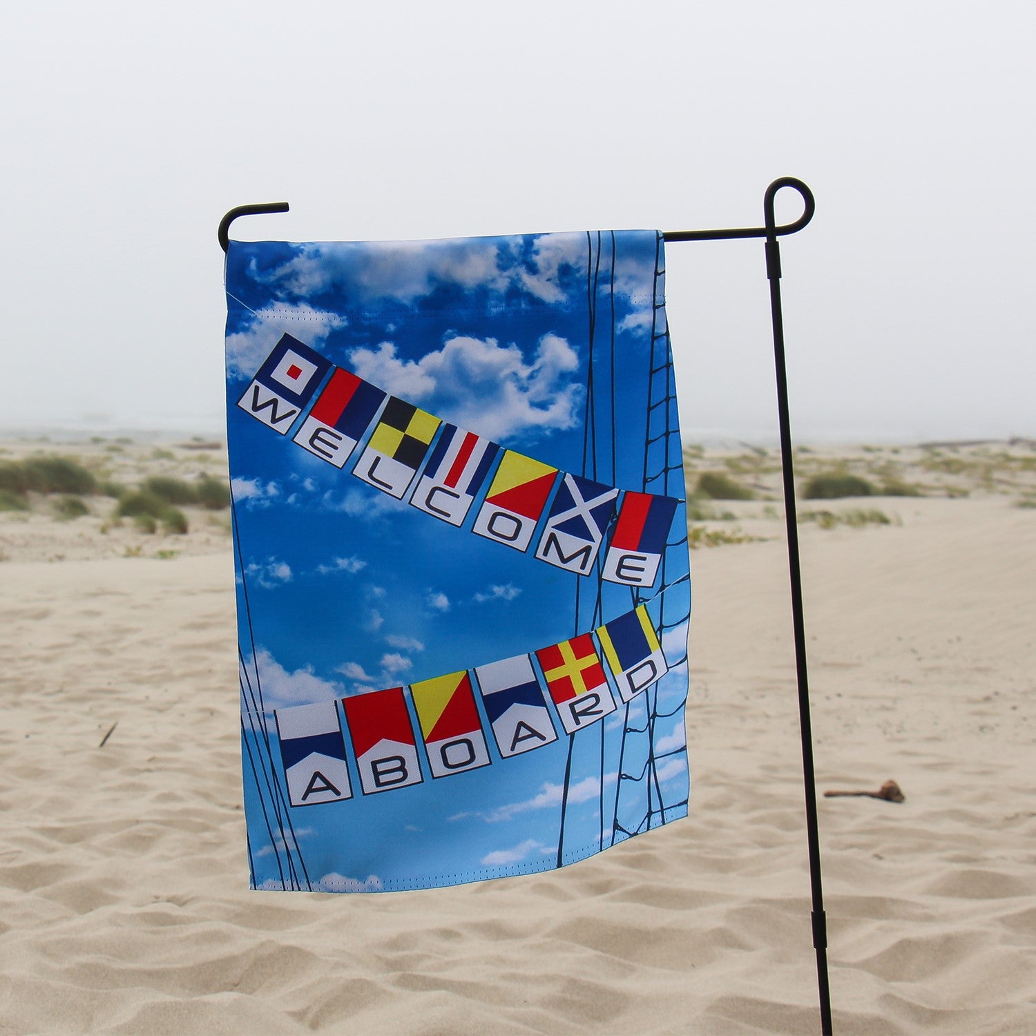 Welcome Aboard Lustre Garden Flag featuring a nautical design, displayed on a garden flag stand in a sunny outdoor setting.