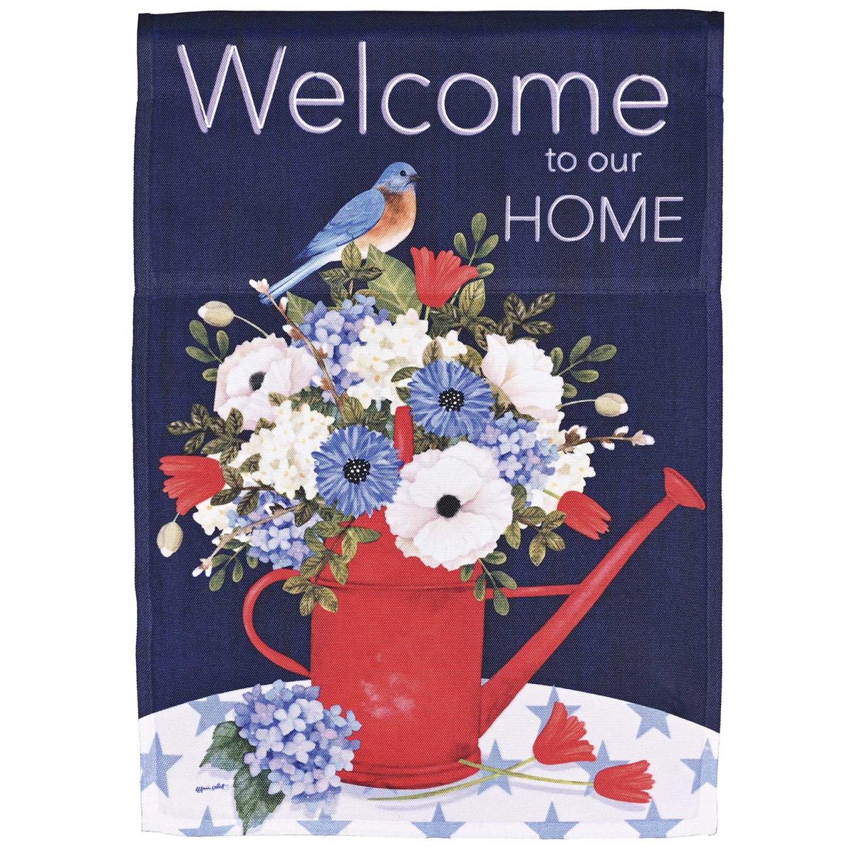 Welcome To Our Home banner flag measuring 30x44 inches in bright colors, hanging beautifully in a garden setting with sunlight illuminating it.