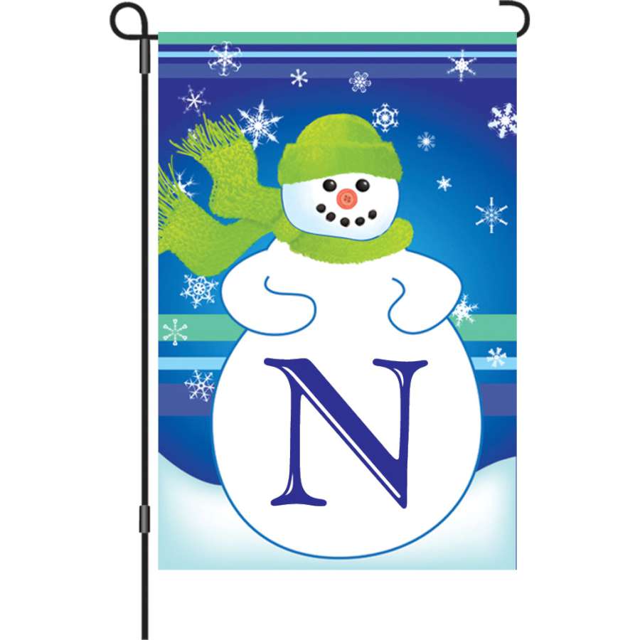 12 in. Winter Monogram Flag - N featuring a whimsical design displayed in a garden setting, enhancing outdoor winter decor.
