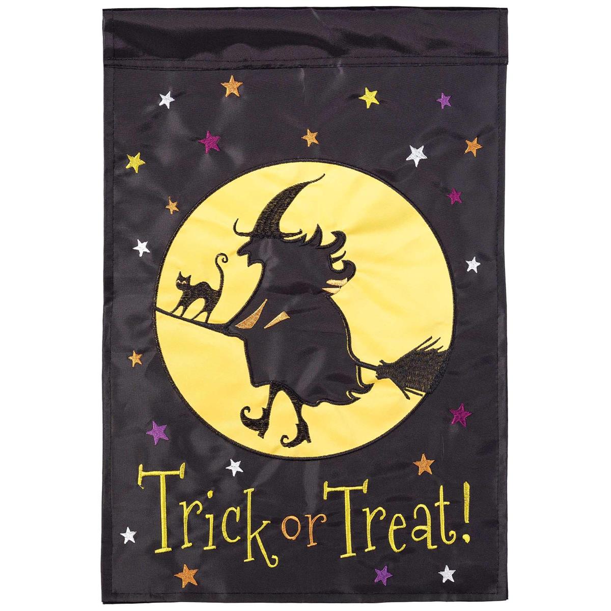 Witch Trick Or Treat double-sided garden flag featuring colorful designs, displayed on a flagpole in a Halloween-themed yard setting.
