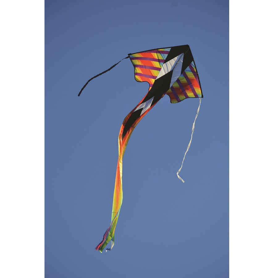 Zephyr Kite - Rainbow Geometric design, 64x165 inches, soaring in a clear blue sky with a picturesque landscape below.