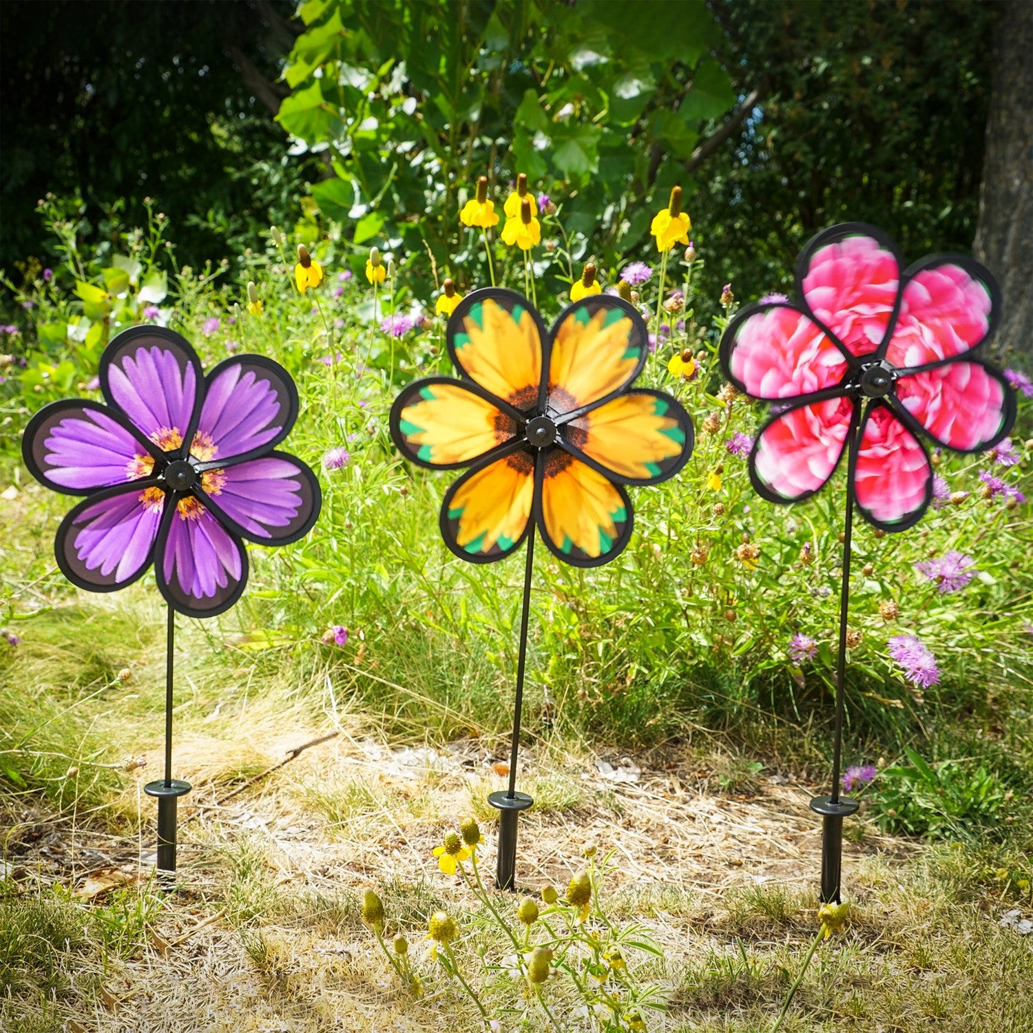 Assorted 10-inch realistic flower spinners showcasing Aster, Sunflower, and Peony designs, gently spinning in an outdoor garden setting.