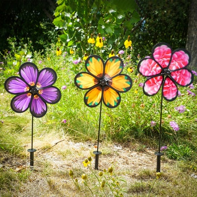Assorted 10-inch realistic flower spinners showcasing Aster, Sunflower, and Peony designs, gently spinning in an outdoor garden setting.