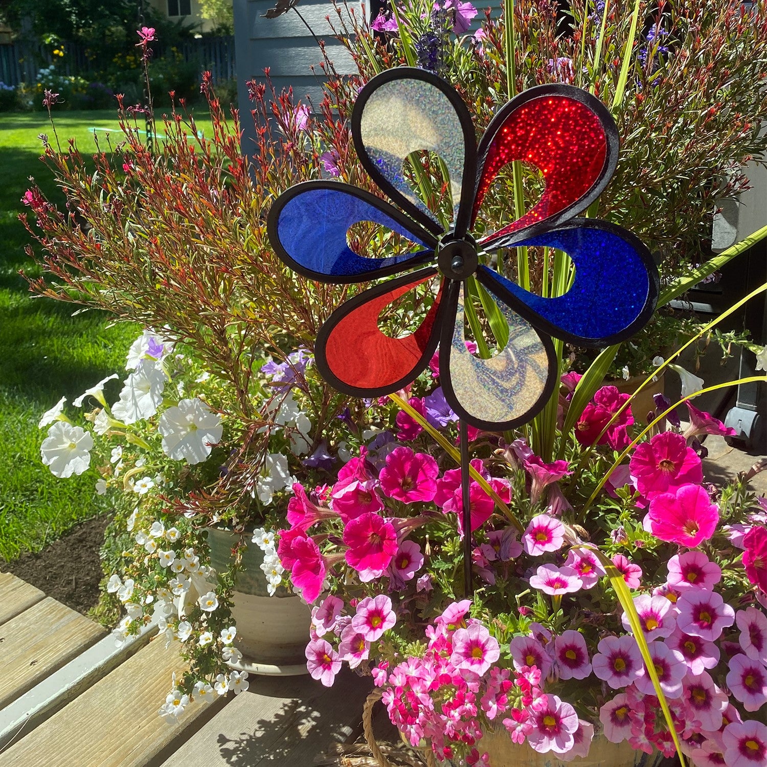 10' Red, White and Blue Mylar Windee Wheelz Spinner with vibrant petals creating an eye-catching spin, displayed outdoors on a sunny day.