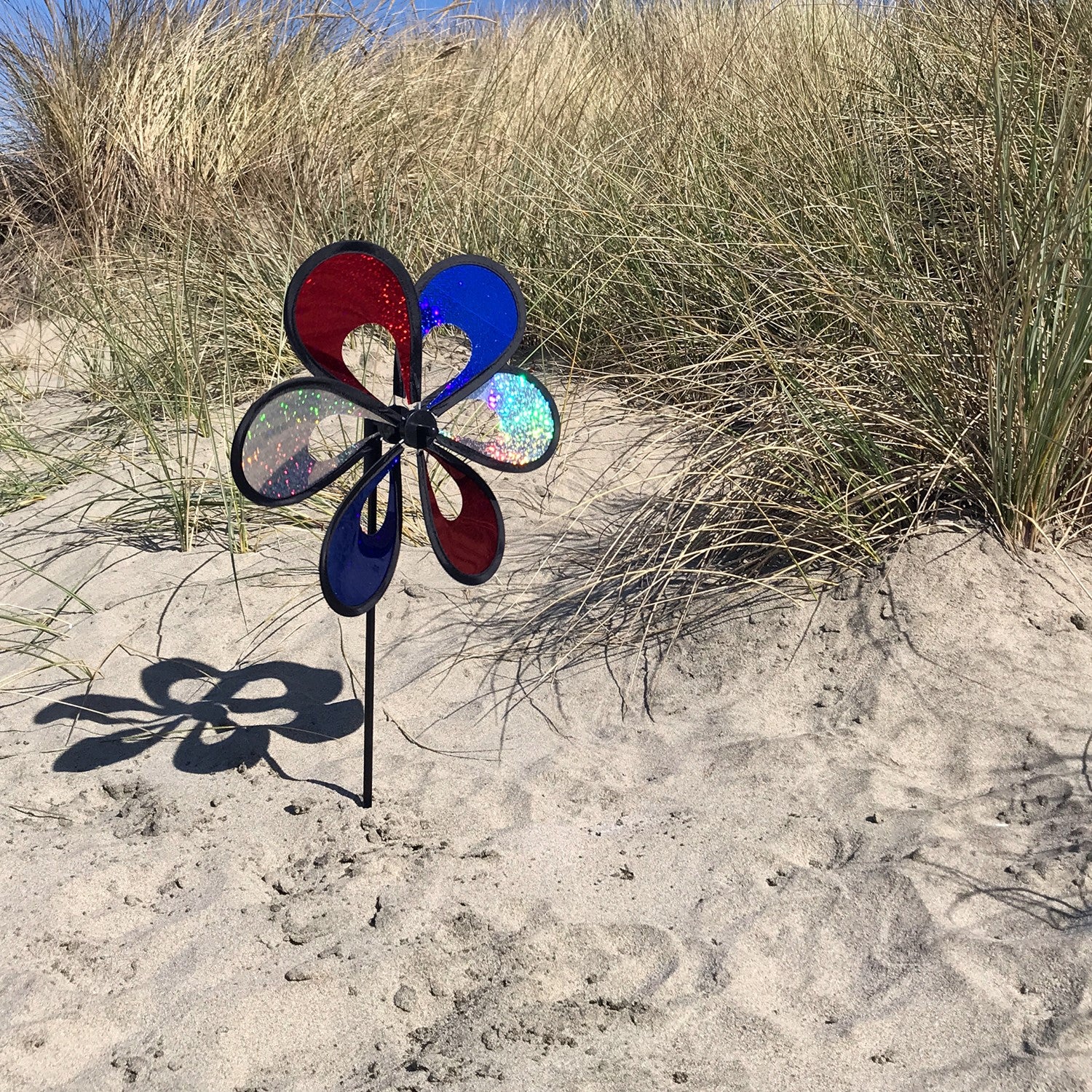 10' Red, White and Blue Mylar Windee Wheelz Spinner with vibrant petals creating an eye-catching spin, displayed outdoors on a sunny day.