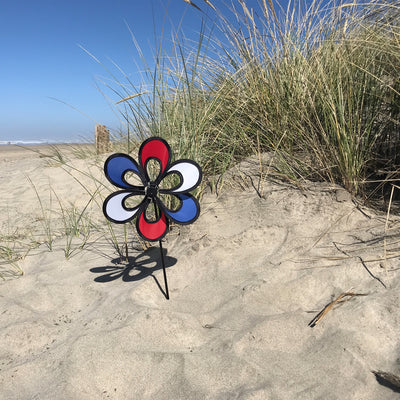 10-inch Red, White and Blue Windee Wheelz Spinner spinning in the garden, featuring an open-center petal design with vibrant colors.