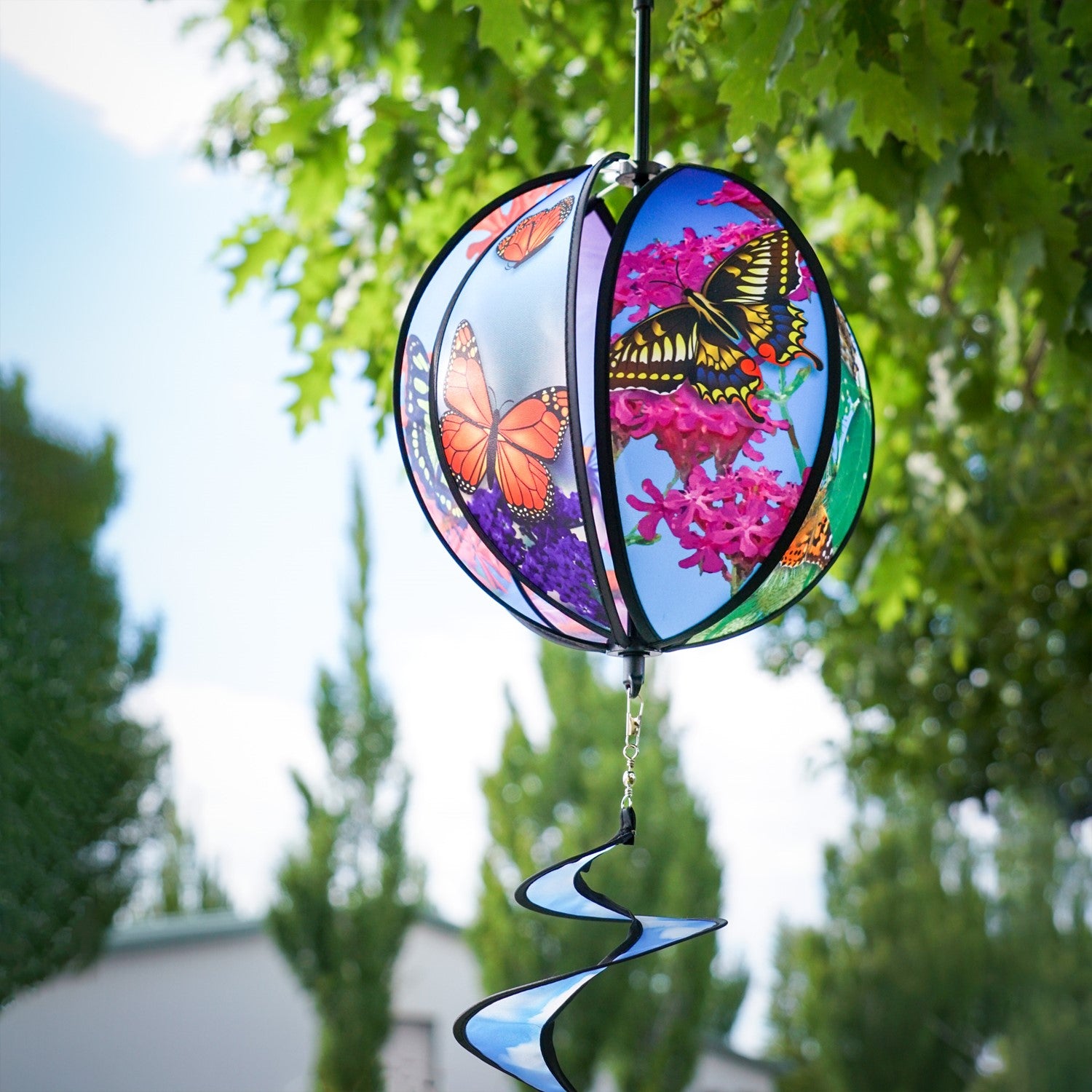 11-inch butterfly hanging ball spinner with six colorful butterfly design panels spinning in a garden setting on a sunny day.