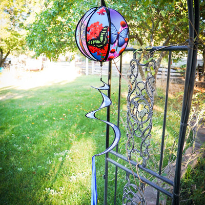 11-inch butterfly hanging ball spinner with six colorful butterfly design panels spinning in a garden setting on a sunny day.