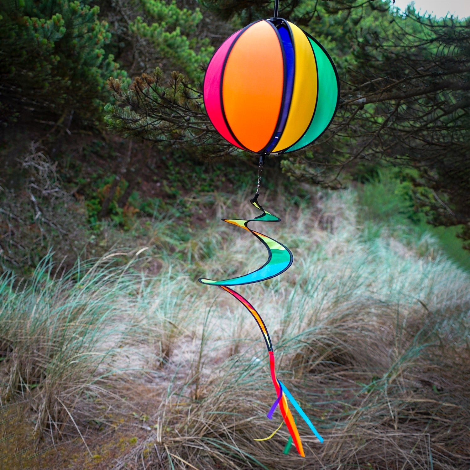 Colorful 11-inch Rainbow-Panel Hanging Ball Spinner displaying six vibrant panels and a curly tail, spinning in the garden under outdoor sunlight.