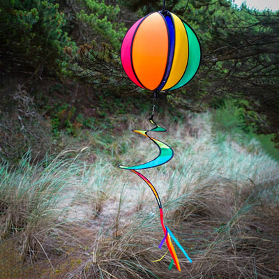 Colorful 11-inch Rainbow-Panel Hanging Ball Spinner displaying six vibrant panels and a curly tail, spinning in the garden under outdoor sunlight.