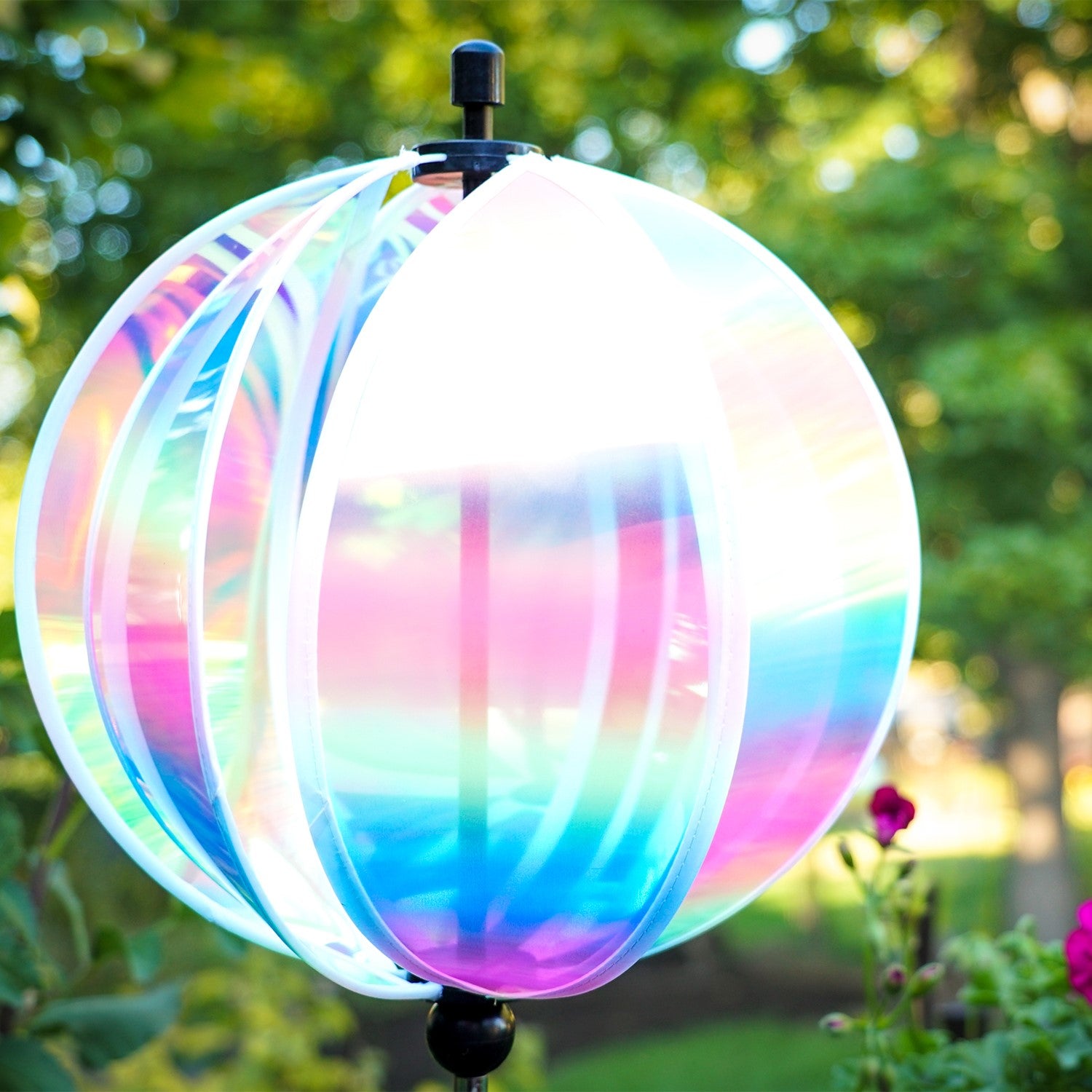 An 11" striped iridescent gazing ball displayed in a garden, featuring colorful reflections and a durable pole for stability.