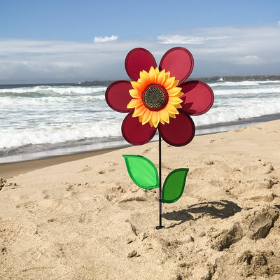 12" burgundy sunflower spinner in vibrant colors with spinning petals displayed in a garden setting, enhancing outdoor decor.