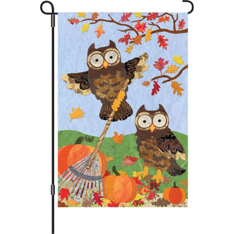 Illuminated 12 in. Autumn Owls flag made of durable polyester showing cute owls surrounded by fall leaves, displayed on a garden flag stand.