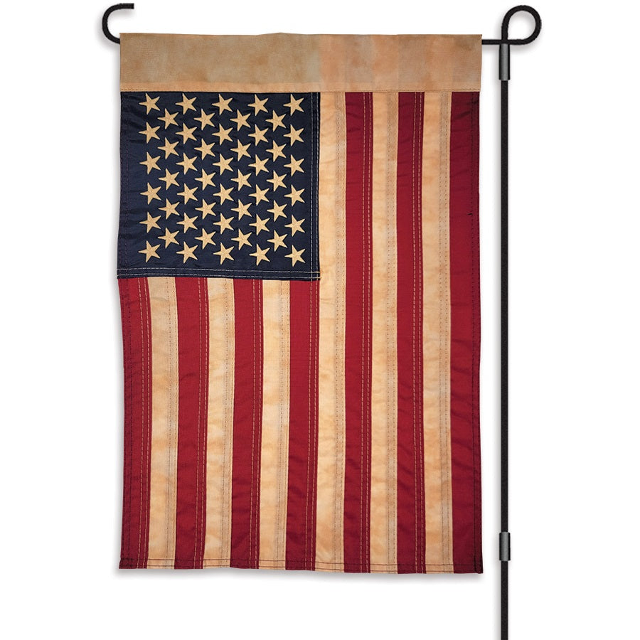 12 in. Embroidered Applique Flag displaying antique-style United States flag with embroidered stars and appliqued stripes in a garden setting.