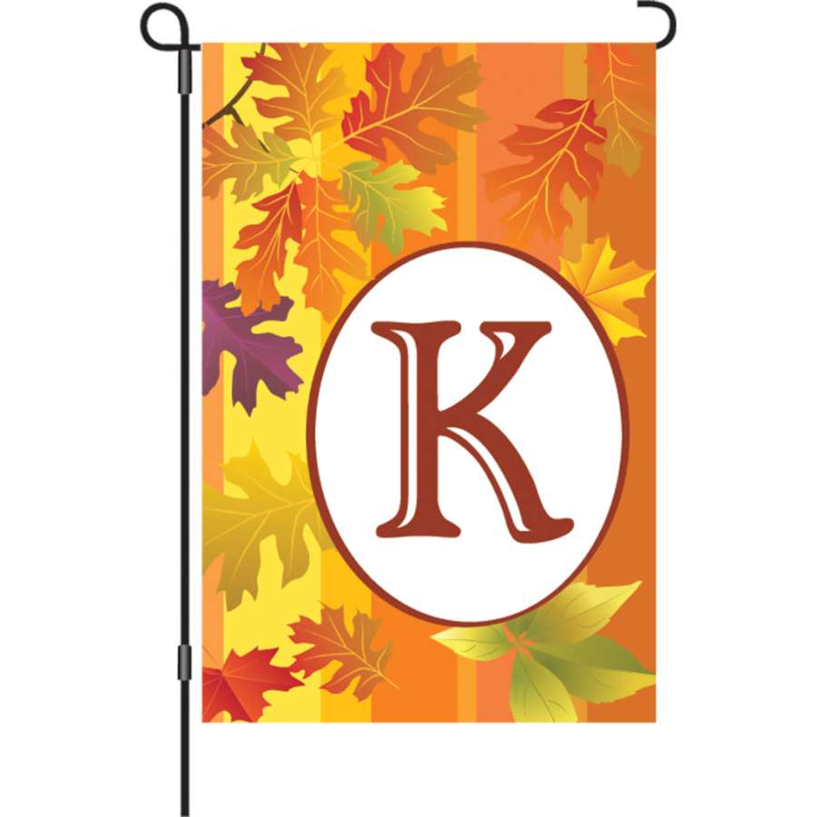12 in. Fall Monogram Flag - K displayed in a garden with vibrant autumn leaves and intricate monogram design, adding seasonal charm.