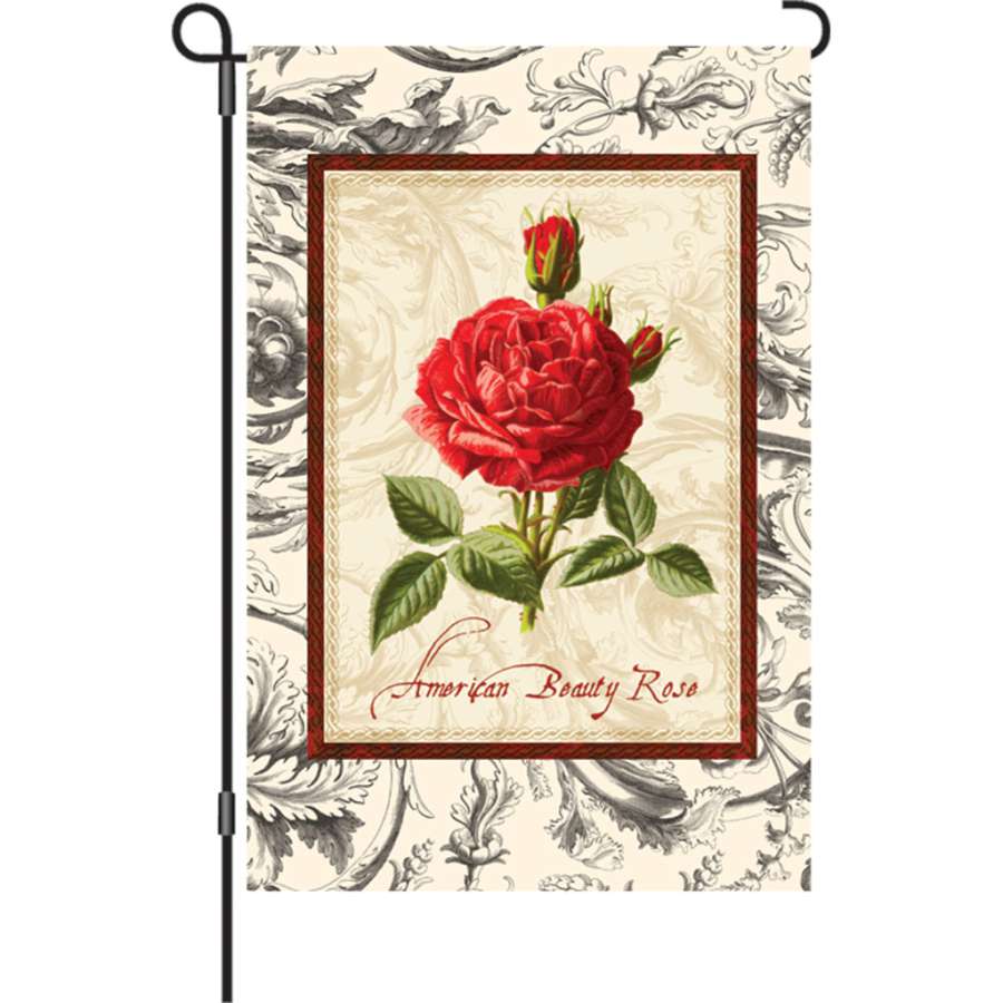 12 in. American Beauty Rose garden flag beautifully displayed in an outdoor garden, showcasing its vivid colors and intricate designs on both sides.