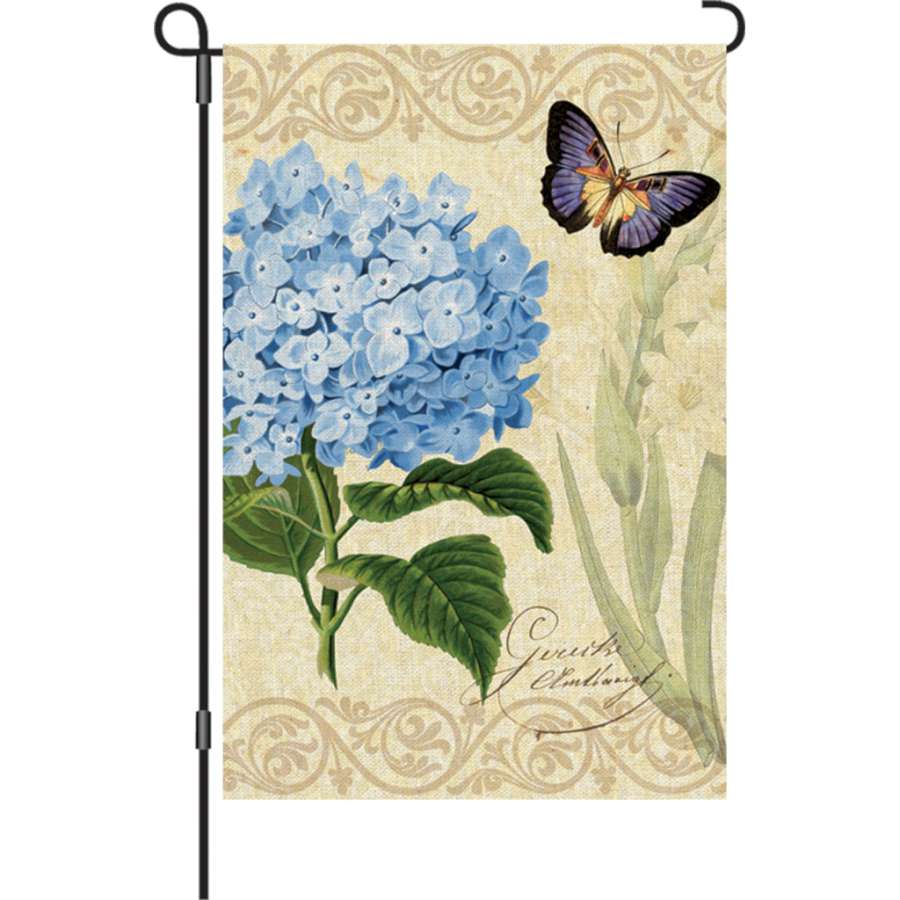12 in. illuminated garden flag with Botanical Fresh Blue floral design, displayed on a flag stand amid lush garden greenery.