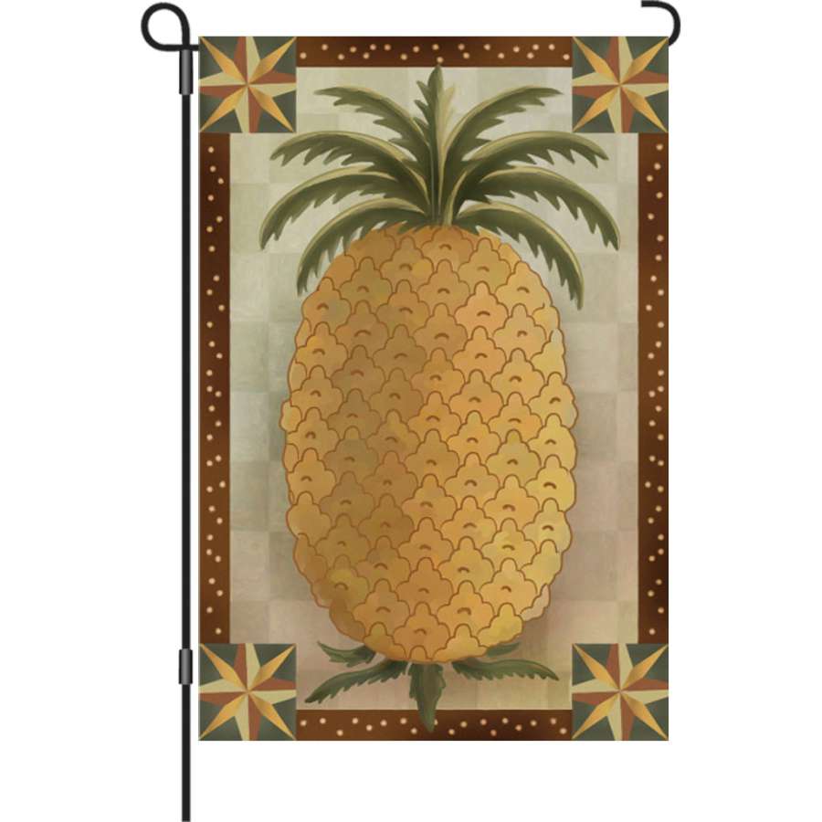 12 in. garden flag featuring a primitive pineapple design, showcasing warm autumn colors, displayed outdoors in a garden setting.