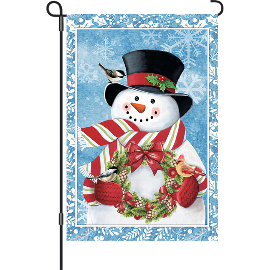 12 in. Flag - Snowman Wreath designed for garden display, featuring an illuminated snowman surrounded by a colorful wreath in a winter setting.