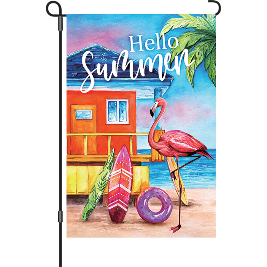 12 in. Flamingo Beach garden flag featuring a colorful flamingo design swaying gently in the summer breeze in a garden setting.