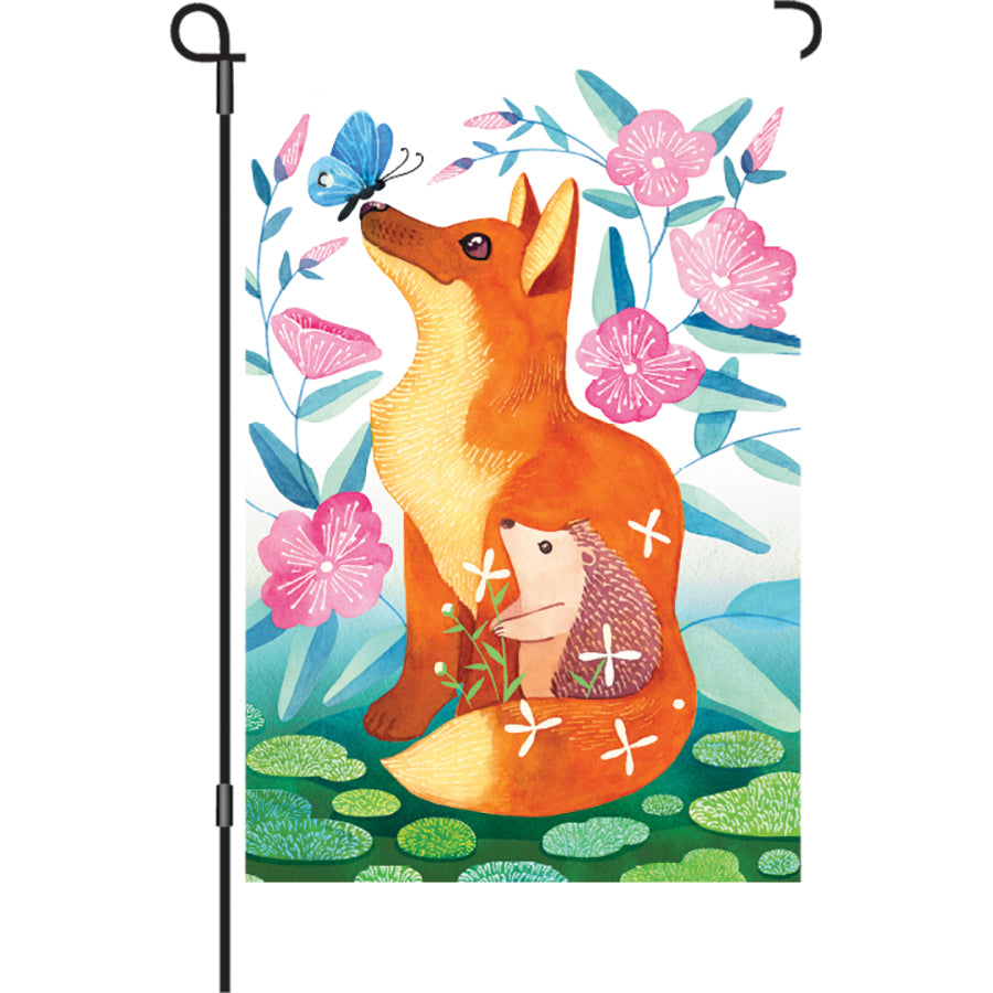 12 in. Fox & Hedgehog garden flag featuring lively colors and illuminating design displayed outdoors, adding charm to a garden.