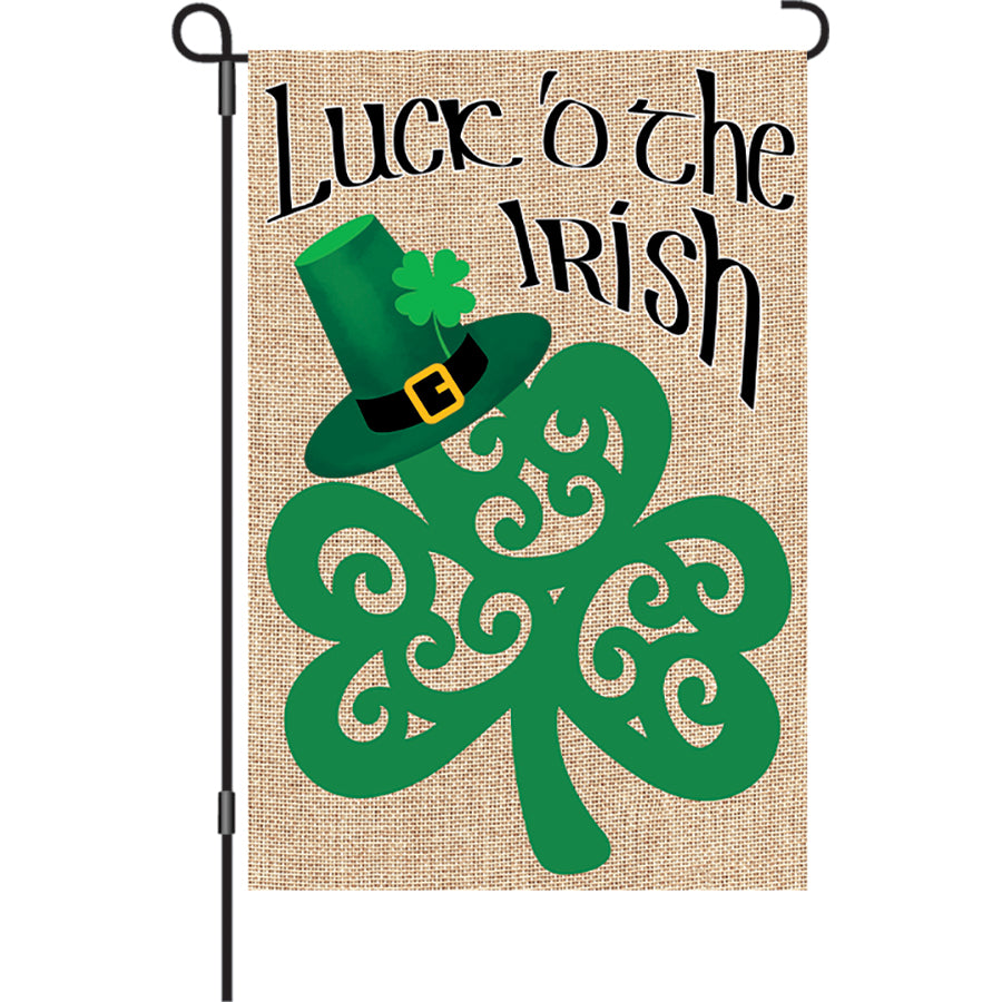 12 in. Shamrock garden flag featuring a vibrant shamrock design against burlap, displayed outdoors in a garden setting.
