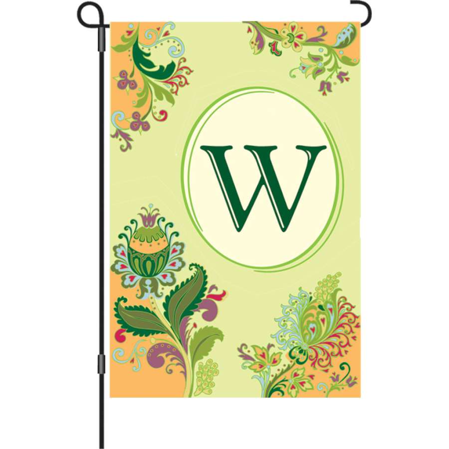 12 in. Spring Monogram Flag - W displayed in a garden setting, featuring a vibrant design with floral elements and a bold letter 'W'.